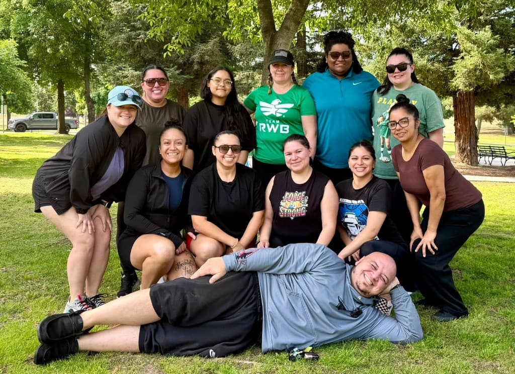 Forge Strength Systems members and their coach posing together outdoors on the grass